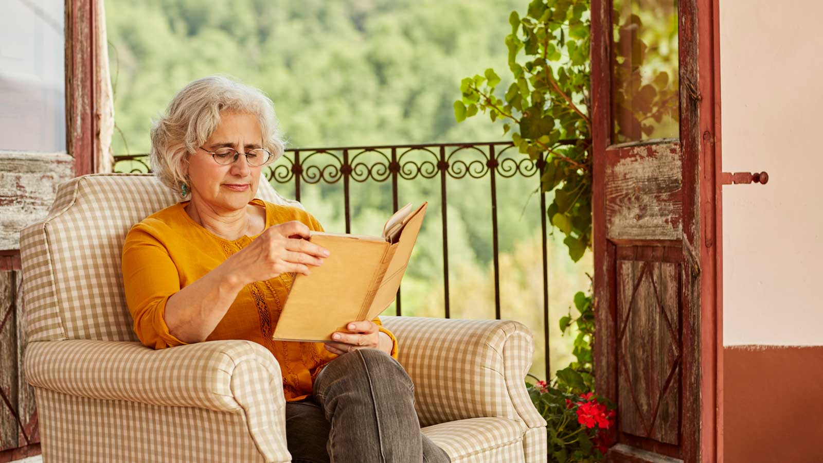 Signora che legge un libro su una poltrona