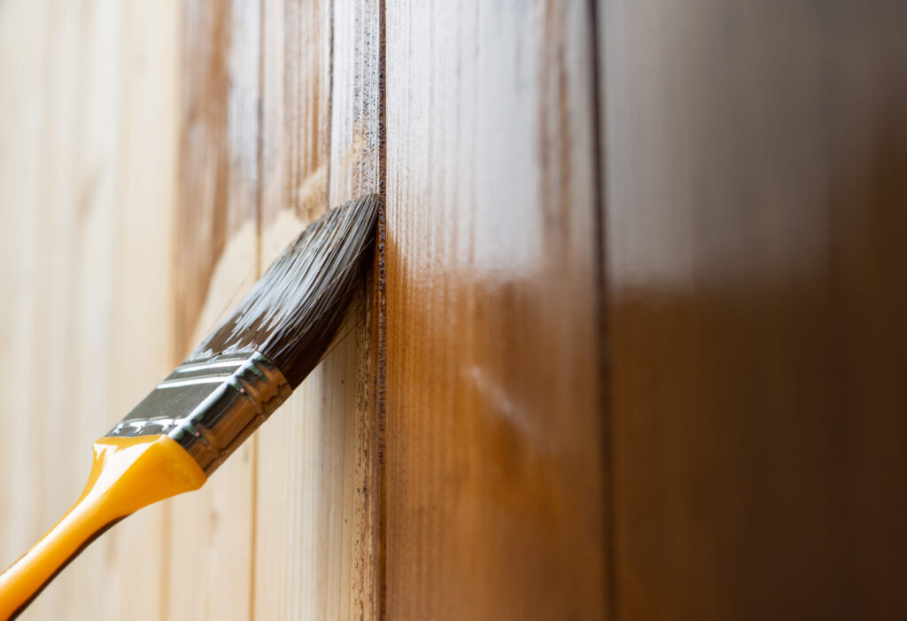 un pennello che stende vernice su una imposta di legno